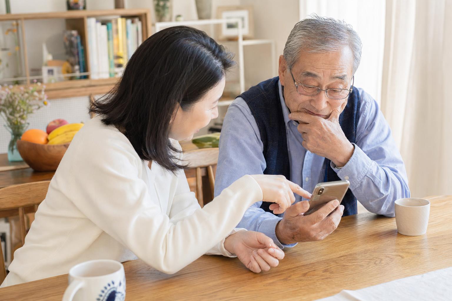 Adult daughter showing her elderly father a check-in app on a smartphone at the dining table